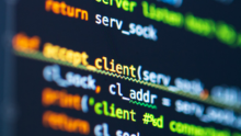 Close-up of computer screen with out-of-focus foreground showing background code, highlighting network programming terms.