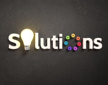 Illuminated light bulb and colorful gears replacing the 'o's, in the word 'Solutions,'on a dark background.